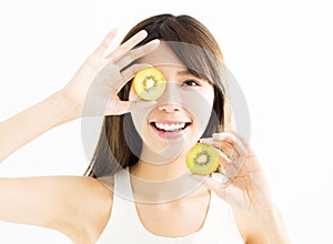 Young woman holding kiwi in front of eyes