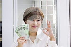 Young woman holding Korean Won with OK sign