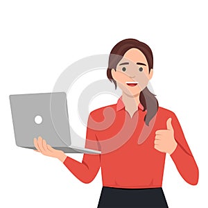 Young woman holding laptop computer and thumbs up gesture. Trendy girl using gadget and showing good or like sign