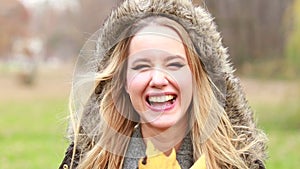 Young woman holding leaf in front of the face, moving it and making funny faces