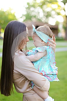 Young woman holding little daughter in green background.