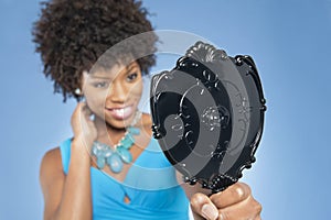 Young woman holding looking at mirror over colored background