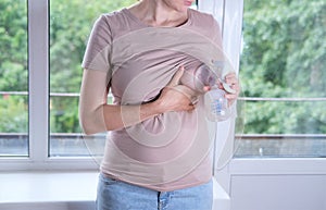 Young woman holding a machine for expressing breast milk. Concept breastfeeding. Breast pump close-up