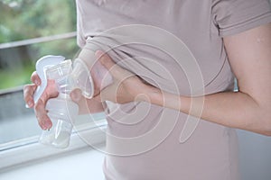 Young woman holding a machine for expressing breast milk. Concept breastfeeding. Breast pump close-up