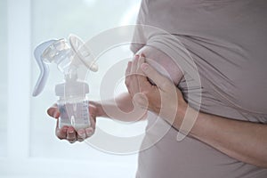 Young woman holding a machine for expressing breast milk. Concept breastfeeding. Breast pump close-up