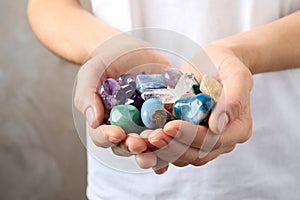 Young woman holding many beautiful gemstones on beige background photo