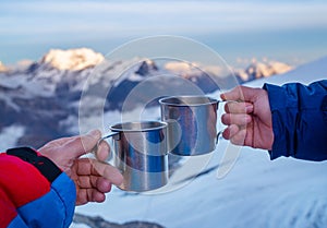 Young woman holding a metal hot tea cup during sunset time from the Mera Peak high camp with snowy seven-thousander mountains. photo