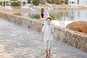 Young woman holding a newborn baby in her arms with teenager on the summer background.Family portrait. Mother and her sons. Baby g