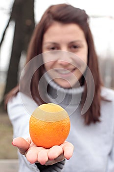 Mujer joven posesión naranja en el parque 