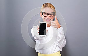 Young woman holding out a cellphone