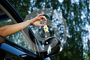 Young woman is holding outside and is about to throw an apple core out of the open car window. Bottom view, against the