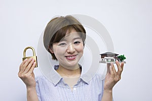 Young woman holding a padlock and a house model