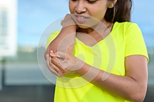 Young woman holding painful elbow