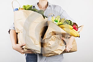 Young woman holding papers shopping bags on gray background