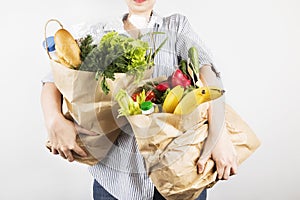Young woman holding papers shopping bags on gray background