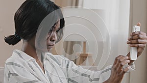 Young woman holding phone thinking making order in online store using mobile app communicates on Internet concentrated