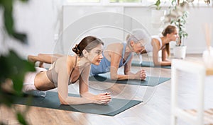 Young woman holding plank pose on forearms in fitness studio