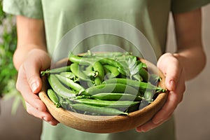 Young woman holding plate with green peas