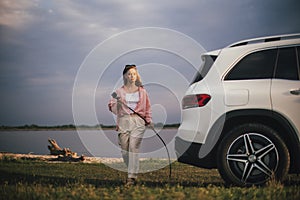 Young woman holding power supply cable from her electric car, prepared for charging it sustainable and economic