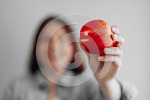 Young woman holding a red apple against a gray wall background. Healthy food diet. Apple vitamin snack.