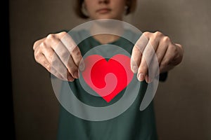 Young woman holding red heart in hands. Health insurance, donation and charity concept, world heart day, fair trade