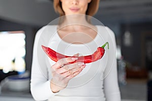 Young woman holding red hot chili pepper in hand