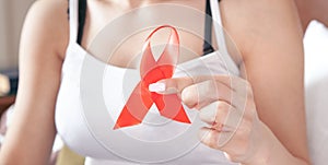 Young woman holding red ribbon HIV. AIDS