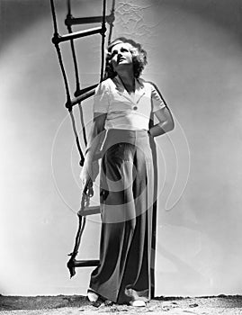 Young woman holding a rope ladder and looking up