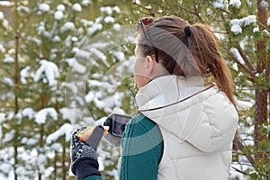 Young woman holding sandwitch and coffee mug in winter forest.