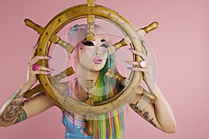 Young woman holding ship's wheel in front of her face