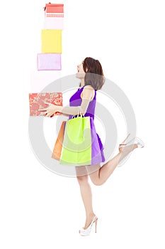 Young woman holding shopping bag and gift boxes over white