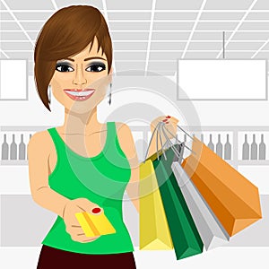 Young woman holding shopping bags and giving a credit card