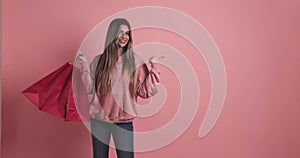 Young woman holding shopping bags pointing aside