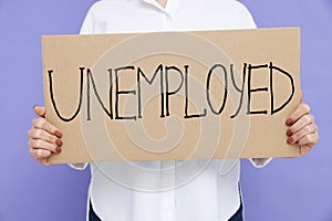 Young woman holding sign with word Unemployed on violet background, closeup