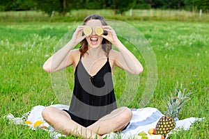 Young woman holding a sliced lemon in front of her eyes