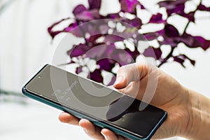 Young woman holding the smartphone in her hand and looking at the clock