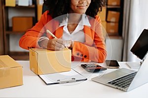 Young woman holding a smartphone showing payment success and credit card with yellow parcel box as online shopping concept in