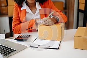 Young woman holding a smartphone showing payment success and credit card with yellow parcel box as online shopping concept in