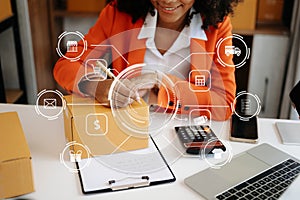 Young woman holding a smartphone showing payment success and credit card with yellow parcel box as online shopping concept in