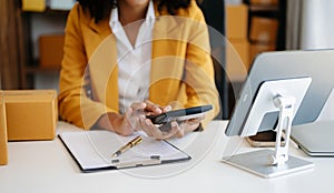 Young woman holding a smartphone showing payment success and credit card with yellow parcel box as online shopping concept in