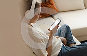 Young woman holding smartphone touching finger mockup white blank display, empty screen for social media app ad at home