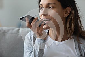 Young woman holding smartphone using voice messaging