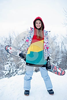 Young woman holding snowboard on her shoulders