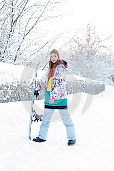 Young woman holding snowboard on her shoulders