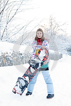 Young woman holding snowboard on her shoulders