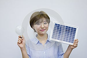 Young woman holding solar panel and light bulb