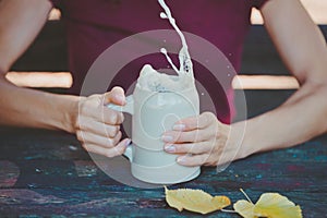 Young woman holding stein clay beer mug with fresh splashing beer in her hands photo