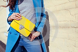 Young woman holding stylish handbag and wearing trendy blue coat. Spring female clothes and accessories. Fashion