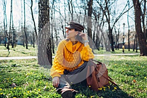 Young woman holding stylish handbag and wearing yellow sweater. Spring female clothes and accessories. Fashion