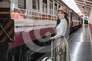 young woman holding a suitcase Happy to travel on holiday by train.